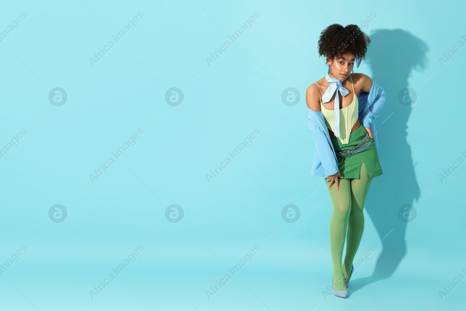 Fashionable portrait of beautiful Brazilian woman in stylish outfit on light blue background. Space for text Photo of Fashionable portrait of beautiful Brazilian woman in stylish outfit on light blue background. Space for text