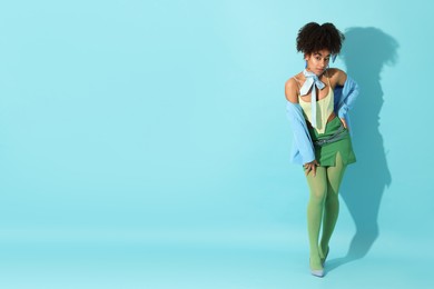 Photo of Fashionable portrait of beautiful Brazilian woman in stylish outfit on light blue background. Space for text