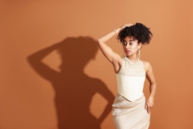 Photo of Fashionable portrait of beautiful Brazilian woman in stylish outfit on light brown background. Space for text