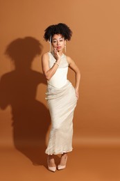 Photo of Fashionable portrait of beautiful Brazilian woman in stylish outfit on light brown background