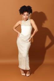 Photo of Fashionable portrait of beautiful Brazilian woman in stylish outfit on light brown background