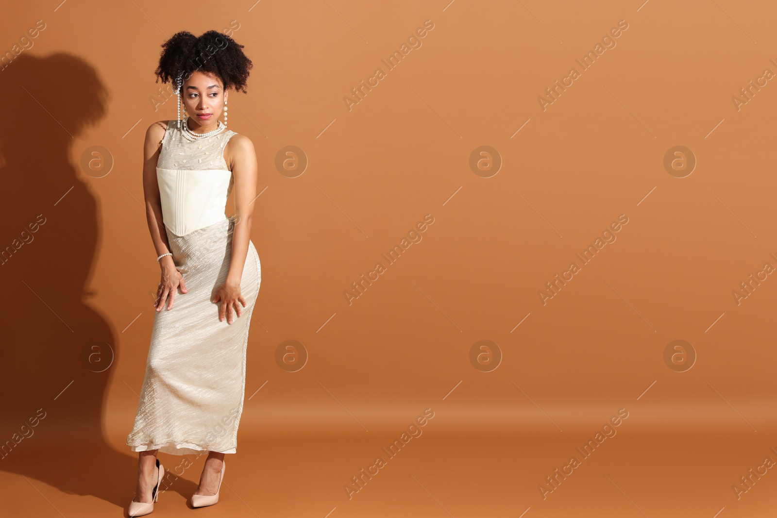 Fashionable portrait of beautiful Brazilian woman in stylish outfit on light brown background. Space for text Photo of Fashionable portrait of beautiful Brazilian woman in stylish outfit on light brown background. Space for text