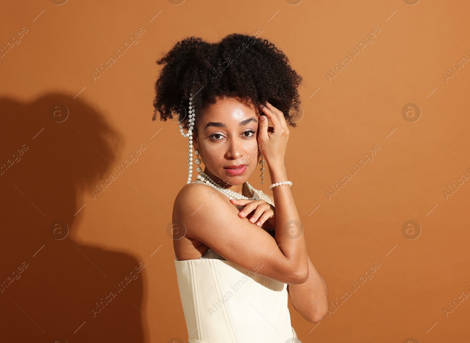 Fashionable portrait of beautiful Brazilian woman in stylish outfit on light brown background Photo of Fashionable portrait of beautiful Brazilian woman in stylish outfit on light brown background