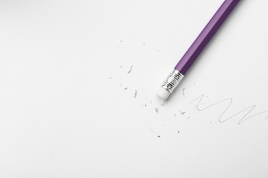 Photo of Pencil with eraser, doodle and scraps on white background, top view. Space for text