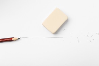 Photo of Pencil, eraser, line and scraps on white paper, flat lay