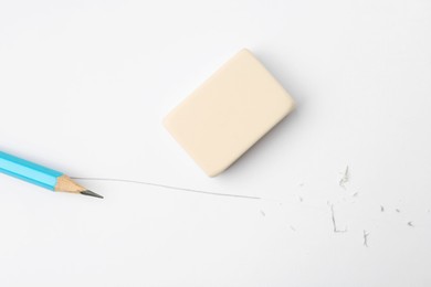 Photo of Pencil, eraser, line and scraps on white paper, flat lay