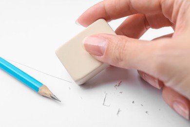 Photo of Woman using eraser at white paper, closeup