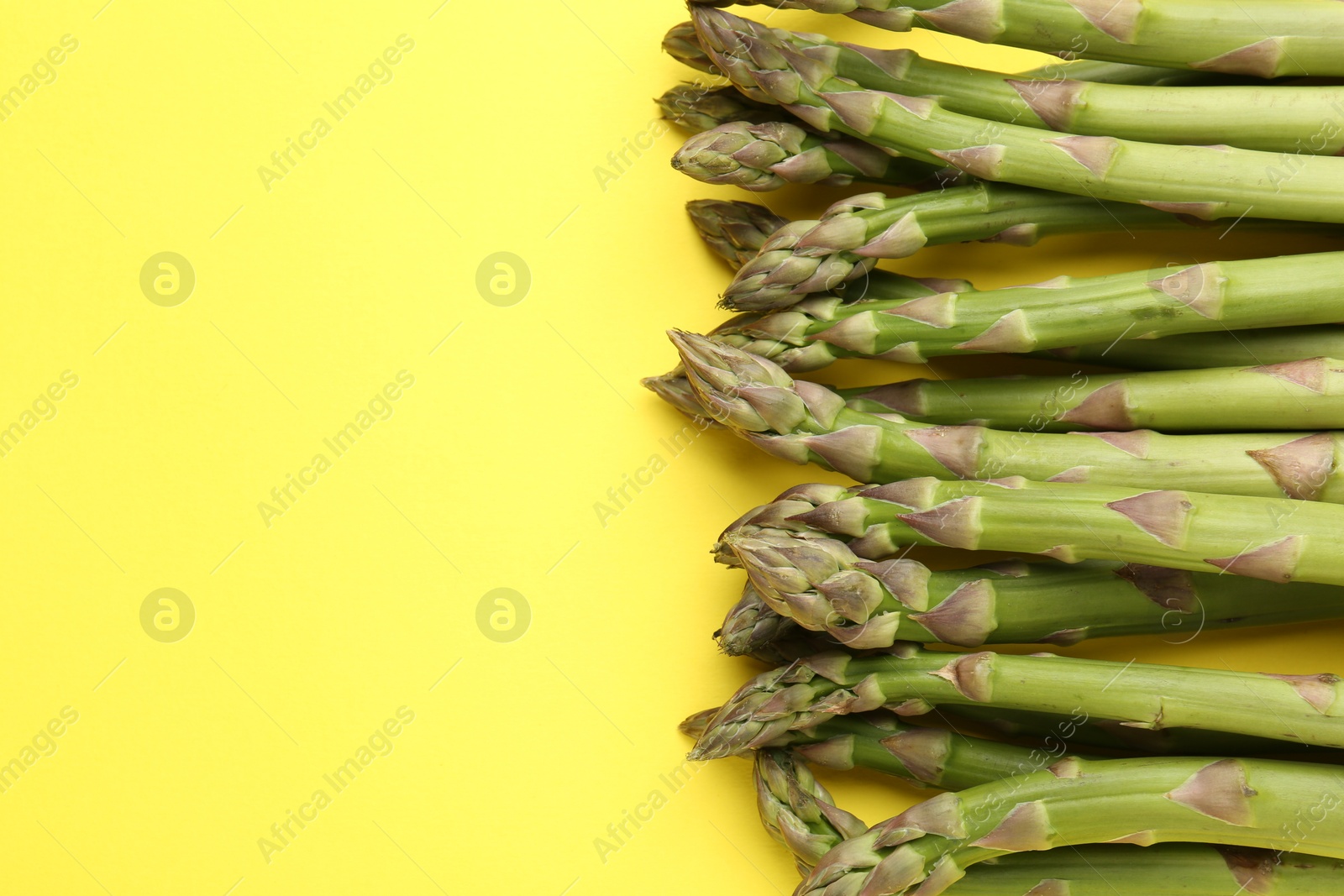 Fresh ripe raw asparagus on yellow background, flat lay. Space for text Photo of Fresh ripe raw asparagus on yellow background, flat lay. Space for text