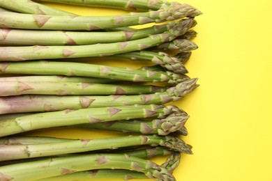 Photo of Fresh ripe raw asparagus on yellow background, flat lay