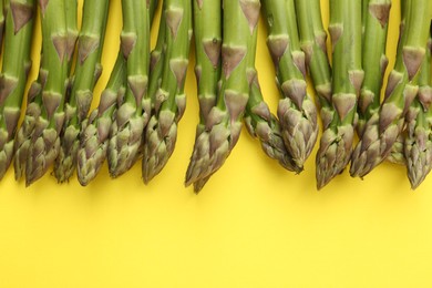 Photo of Fresh ripe raw asparagus on yellow background, flat lay