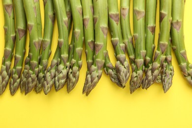 Photo of Fresh ripe raw asparagus on yellow background, flat lay