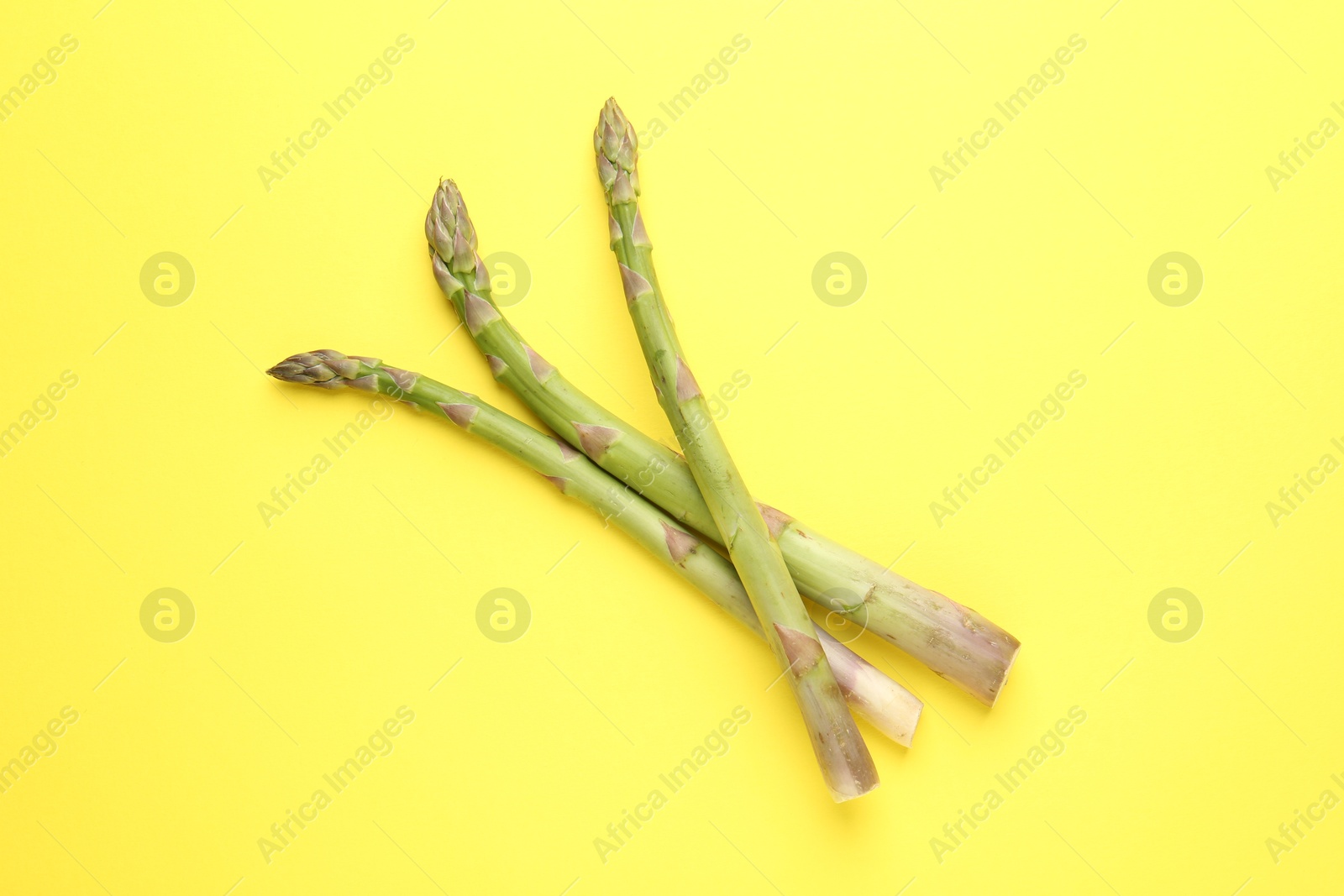 Fresh ripe raw asparagus on yellow background, top view Photo of Fresh ripe raw asparagus on yellow background, top view