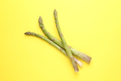 Photo of Fresh ripe raw asparagus on yellow background, top view