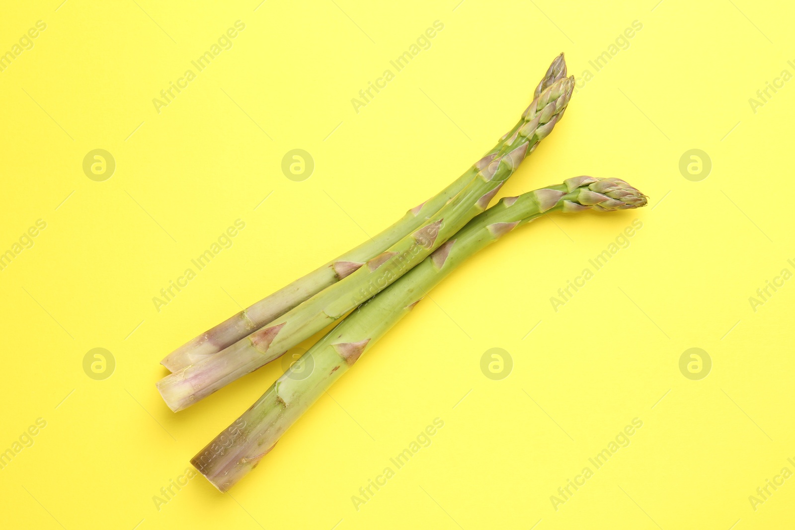 Fresh ripe raw asparagus on yellow background, top view Photo of Fresh ripe raw asparagus on yellow background, top view