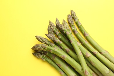 Photo of Fresh ripe raw asparagus on yellow background, top view. Space for text
