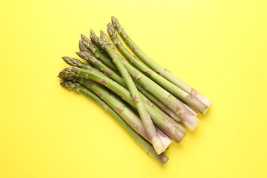 Photo of Fresh ripe raw asparagus on yellow background, top view