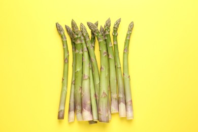 Photo of Fresh ripe raw asparagus on yellow background, top view