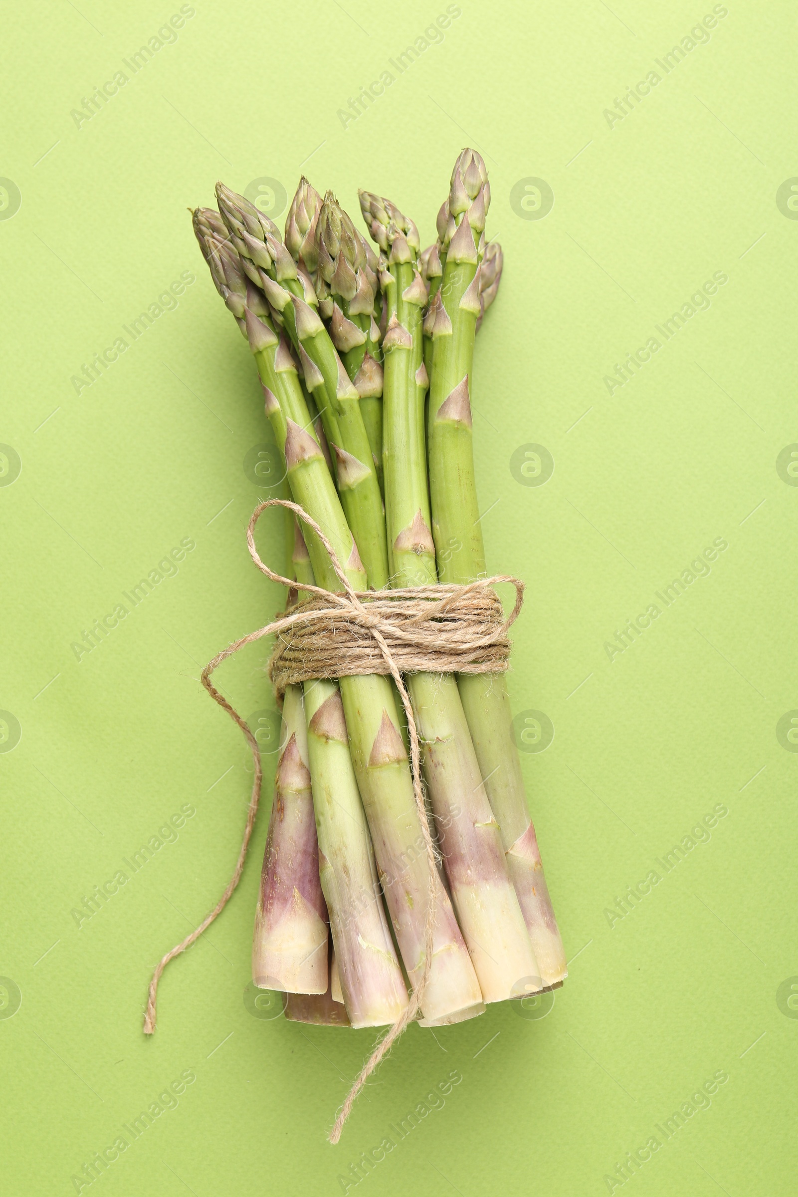 Tied raw asparagus on green background, top view Photo of Tied raw asparagus on green background, top view