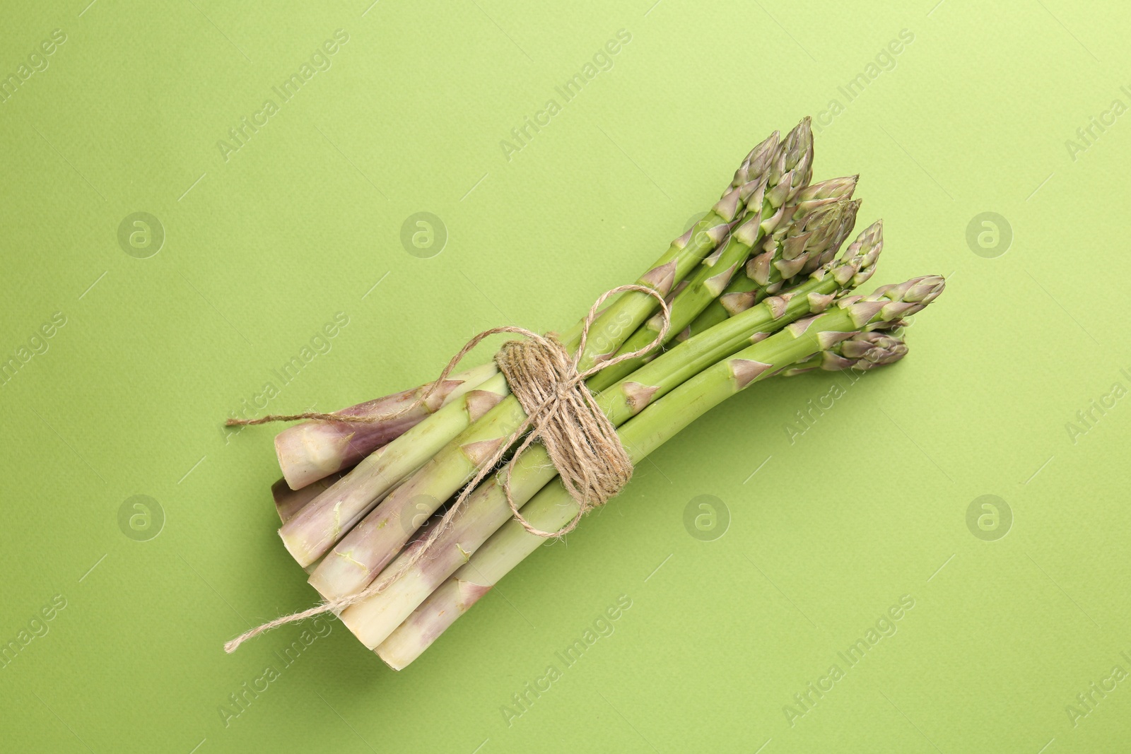 Tied raw asparagus on green background, top view Photo of Tied raw asparagus on green background, top view