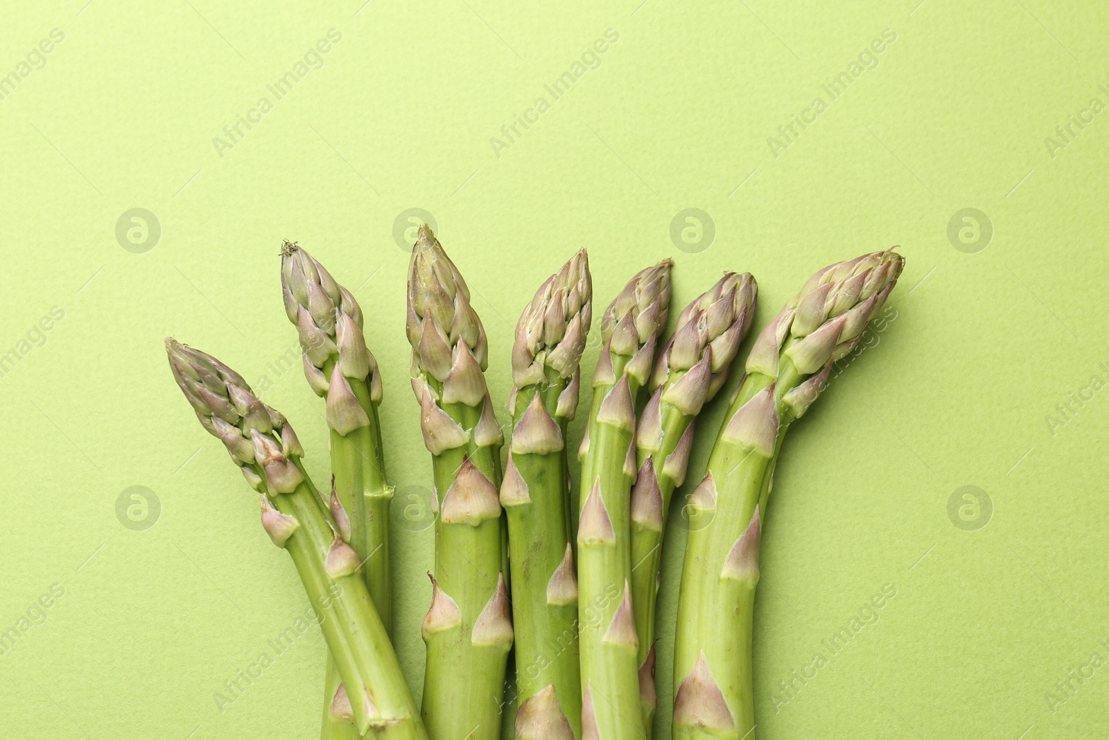 Fresh ripe raw asparagus on green background, top view Photo of Fresh ripe raw asparagus on green background, top view