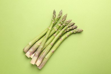 Photo of Fresh ripe raw asparagus on green background, top view