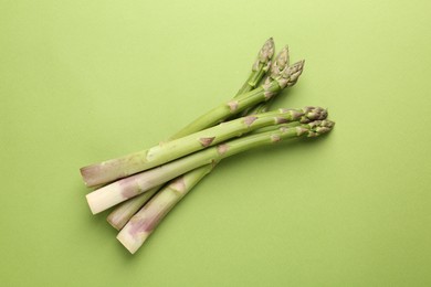 Photo of Fresh ripe raw asparagus on green background, top view