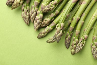 Photo of Fresh ripe raw asparagus on green background, closeup. Space for text
