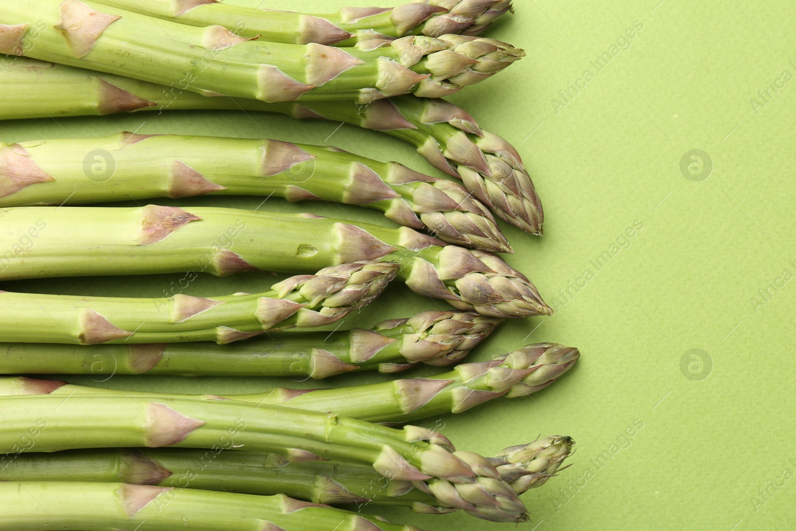 Fresh ripe raw asparagus on green background, closeup Photo of Fresh ripe raw asparagus on green background, closeup