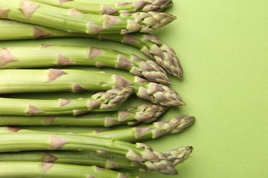 Photo of Fresh ripe raw asparagus on green background, closeup
