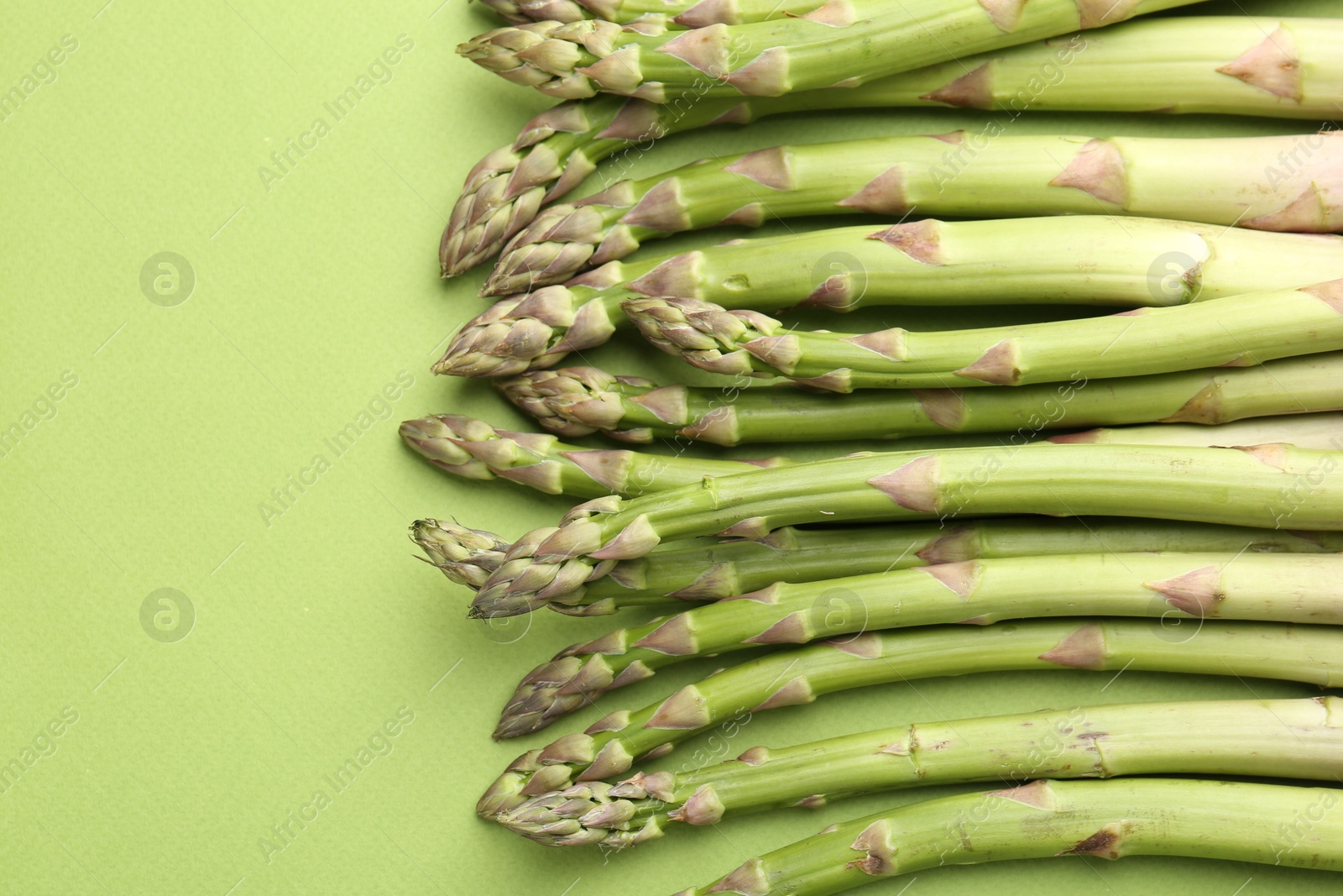 Fresh ripe raw asparagus on green background, closeup Photo of Fresh ripe raw asparagus on green background, closeup