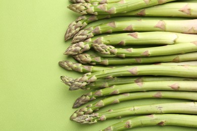 Photo of Fresh ripe raw asparagus on green background, closeup