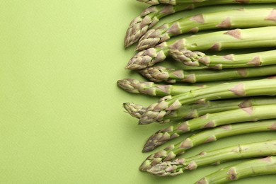 Photo of Fresh ripe raw asparagus on green background, closeup. Space for text