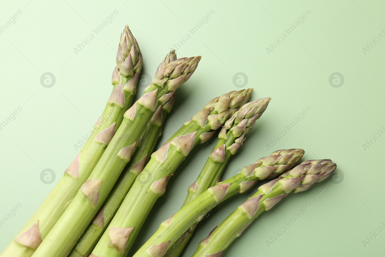Fresh ripe raw asparagus on green background, closeup Photo of Fresh ripe raw asparagus on green background, closeup