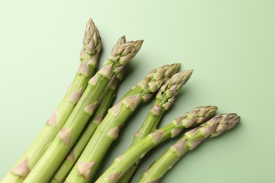 Photo of Fresh ripe raw asparagus on green background, closeup