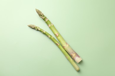 Photo of Fresh ripe raw asparagus on green background, top view