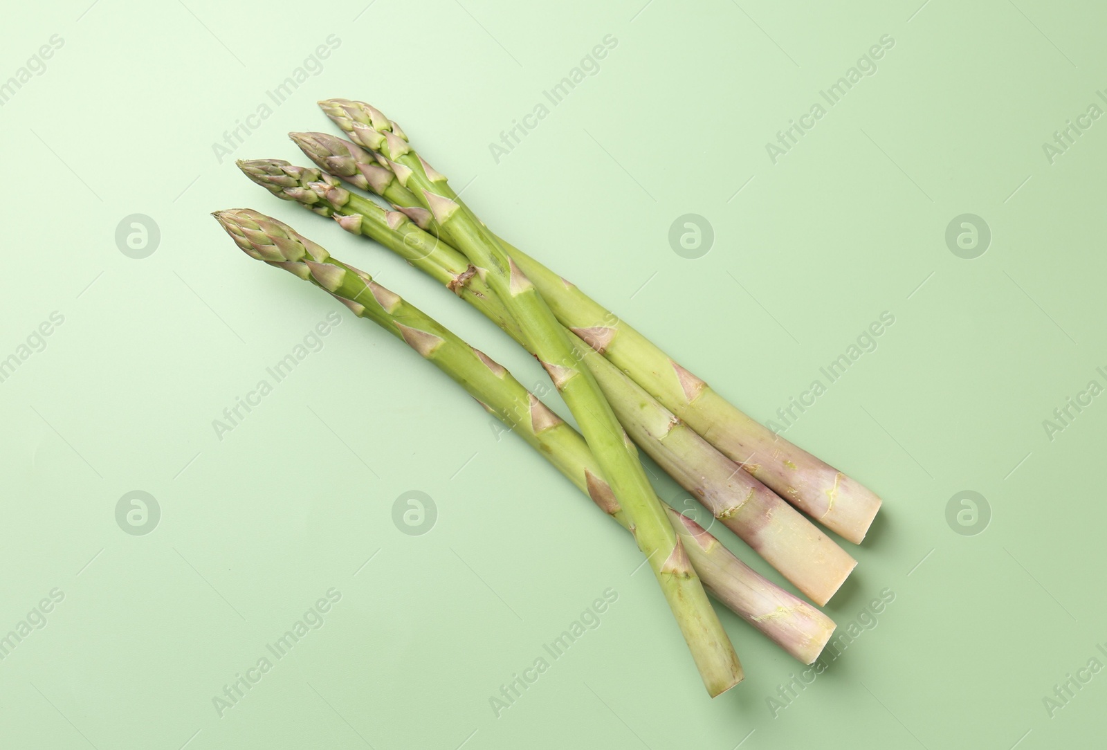 Fresh ripe raw asparagus on green background, top view Photo of Fresh ripe raw asparagus on green background, top view