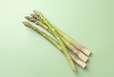 Photo of Fresh ripe raw asparagus on green background, top view