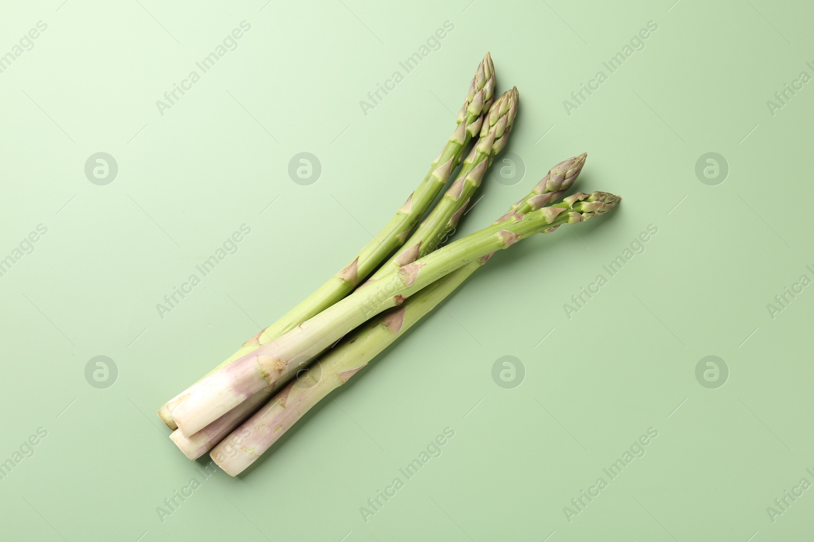 Fresh ripe raw asparagus on green background, top view Photo of Fresh ripe raw asparagus on green background, top view