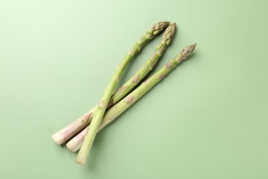 Photo of Fresh ripe raw asparagus on green background, top view