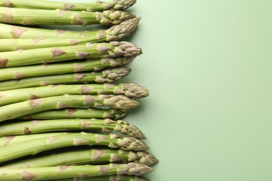 Photo of Fresh ripe raw asparagus on green background, closeup. Space for text