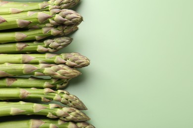 Photo of Fresh ripe raw asparagus on green background, closeup. Space for text