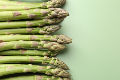 Photo of Fresh ripe raw asparagus on green background, closeup. Space for text