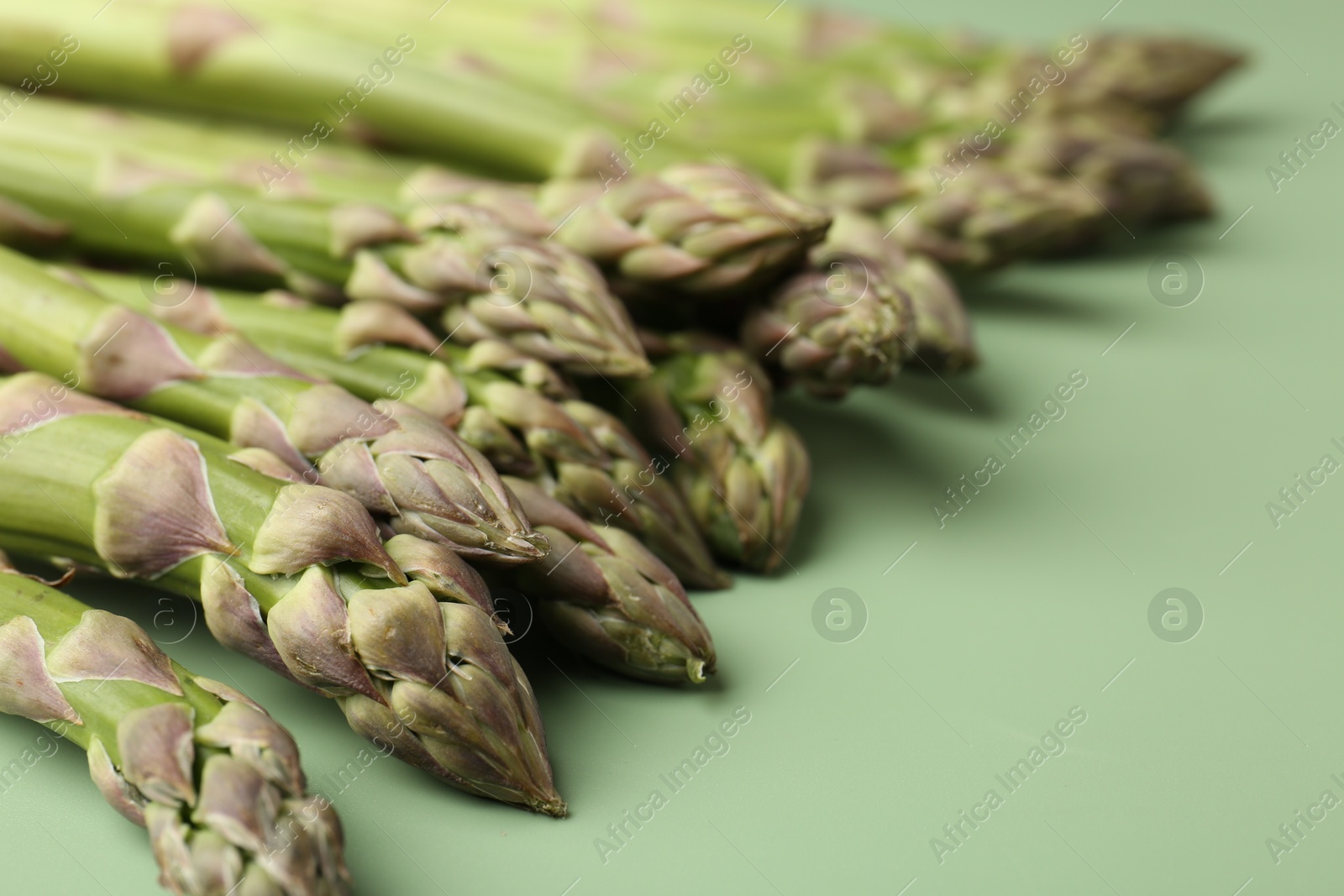 Fresh ripe raw asparagus on green background, closeup Photo of Fresh ripe raw asparagus on green background, closeup