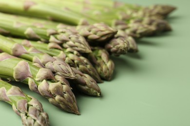 Photo of Fresh ripe raw asparagus on green background, closeup