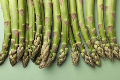 Photo of Fresh ripe raw asparagus on green background, closeup