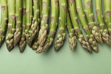 Photo of Fresh ripe raw asparagus on green background, closeup