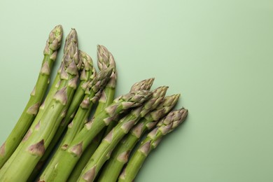 Photo of Fresh ripe raw asparagus on green background, closeup. Space for text