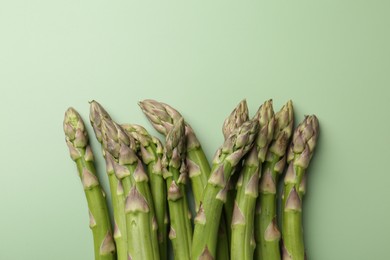 Photo of Fresh ripe raw asparagus on green background, closeup. Space for text