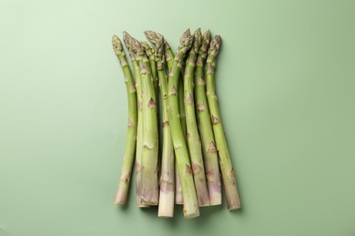 Photo of Fresh ripe raw asparagus on green background, flat lay