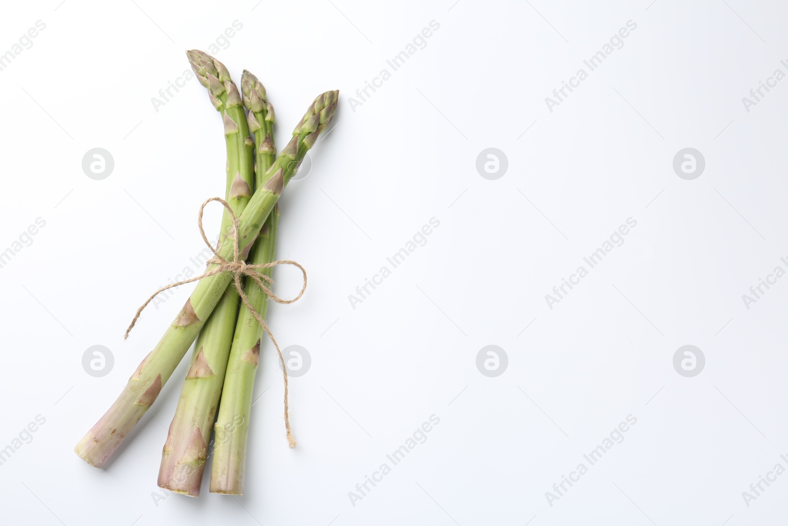 Fresh ripe raw asparagus on white background, top view. Space for text Photo of Fresh ripe raw asparagus on white background, top view. Space for text